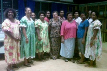 A group of about ten women standing together indoors