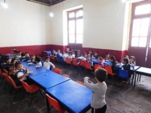 Young schoolchildren seated at blue tables in a classroom