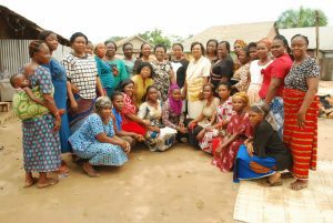 A large group of women and children seated and standing outdoors in a compound