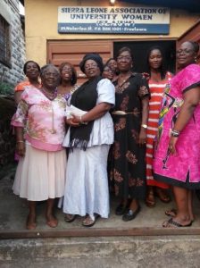 Women standing beneath a Sierra Leone Association of University Women banner